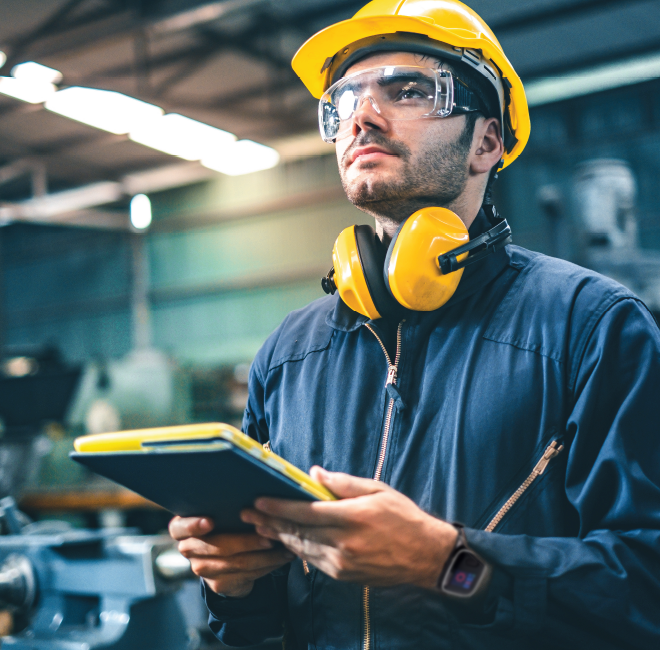 engineer wearing hard hat, ear defenders around neck and a safety watch